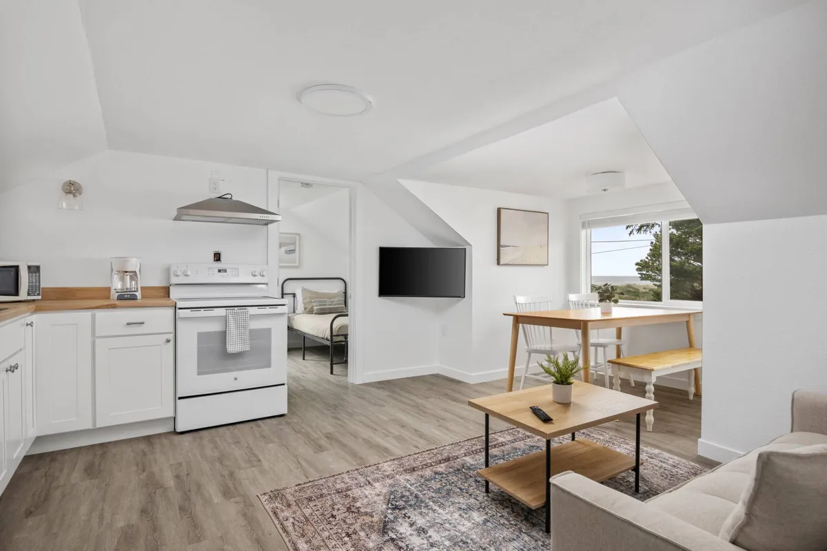 This image showcases the open-concept interior living space, prominently featuring the kitchen area, a dining table perfect for meals or game nights, and a comfortable living area with a couch. The space is bright, modern, and inviting, embodying the sense of togetherness described in the section.