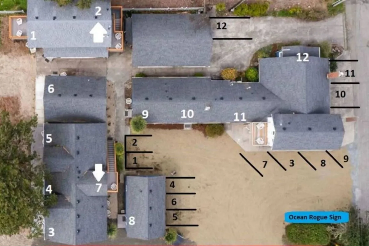 A spacious outdoor area with the main building structure, sandy pathways connecting various units, and ample gathering space. The setting conveys a sense of community and openness, ideal for group events or spontaneous gatherings.