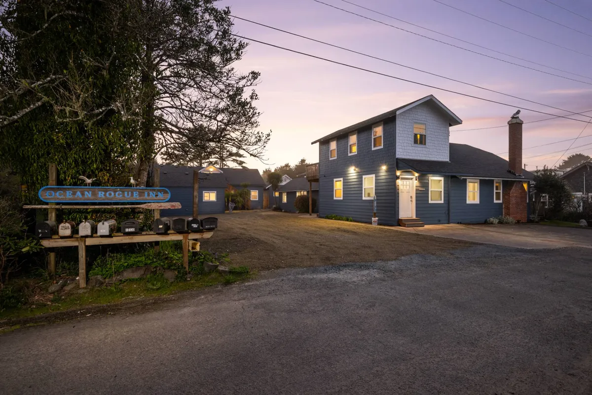 The welcoming Ocean Rogue Inn sign and main entrance, surrounded by mature trees and mailboxes, set a friendly, inviting tone for arrival and exploration. The sight of the sign and entry underscores the inn's place as a hub for families venturing to the beach and downtown attractions.